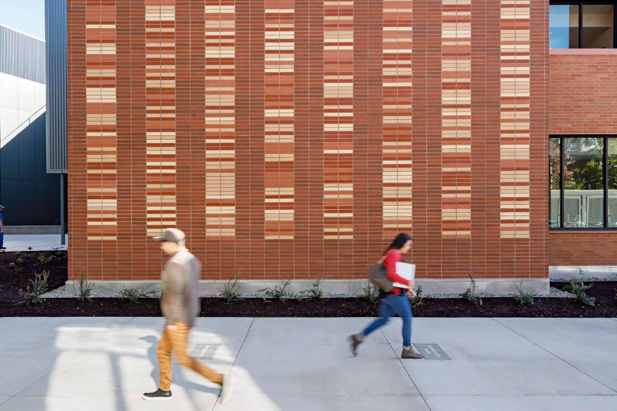 Two students walking past each other outside DeJardin Hall