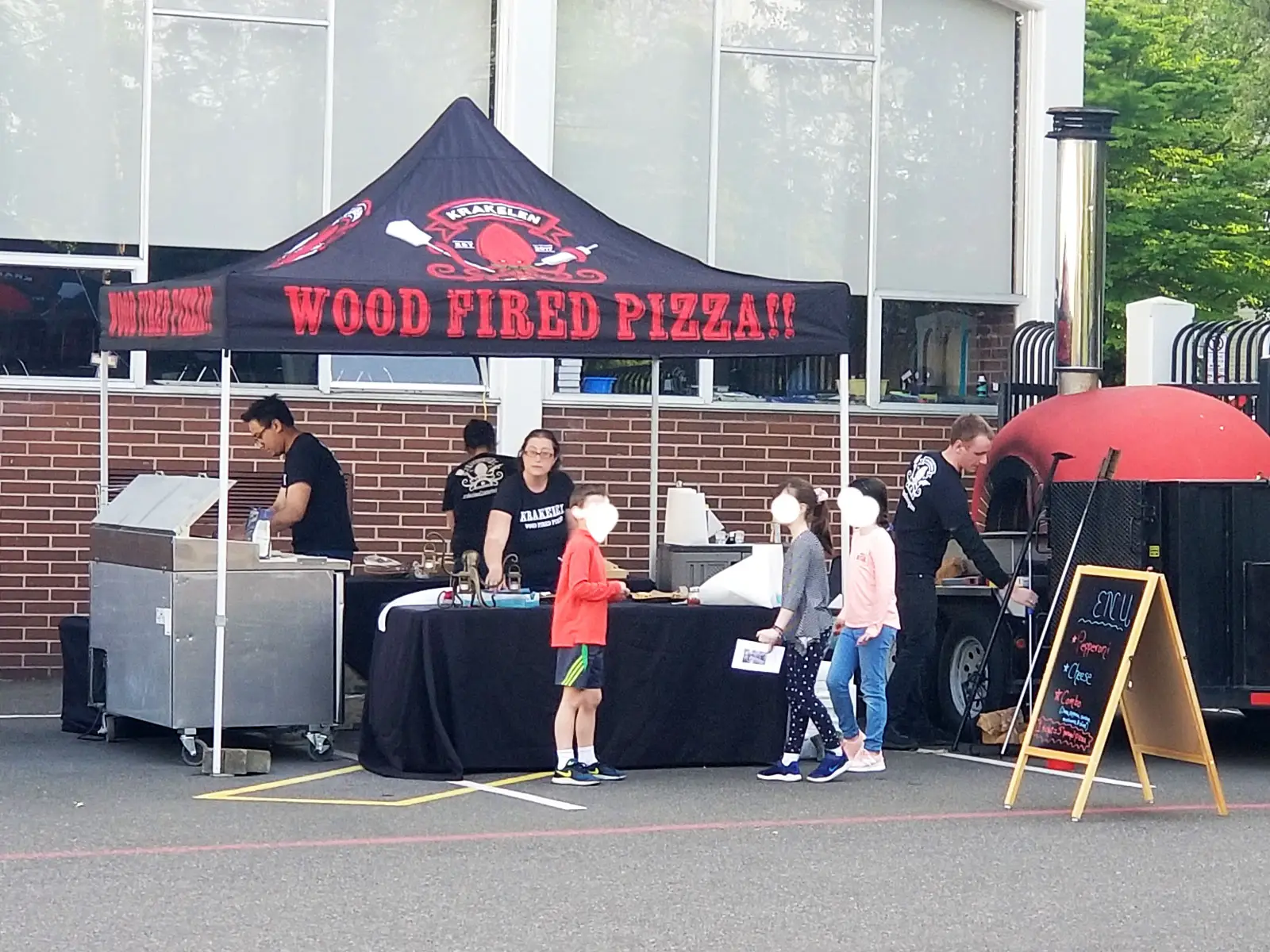A Krakelen pizza food tent with staff using a grill and wood oven, at the Wilsonville campus