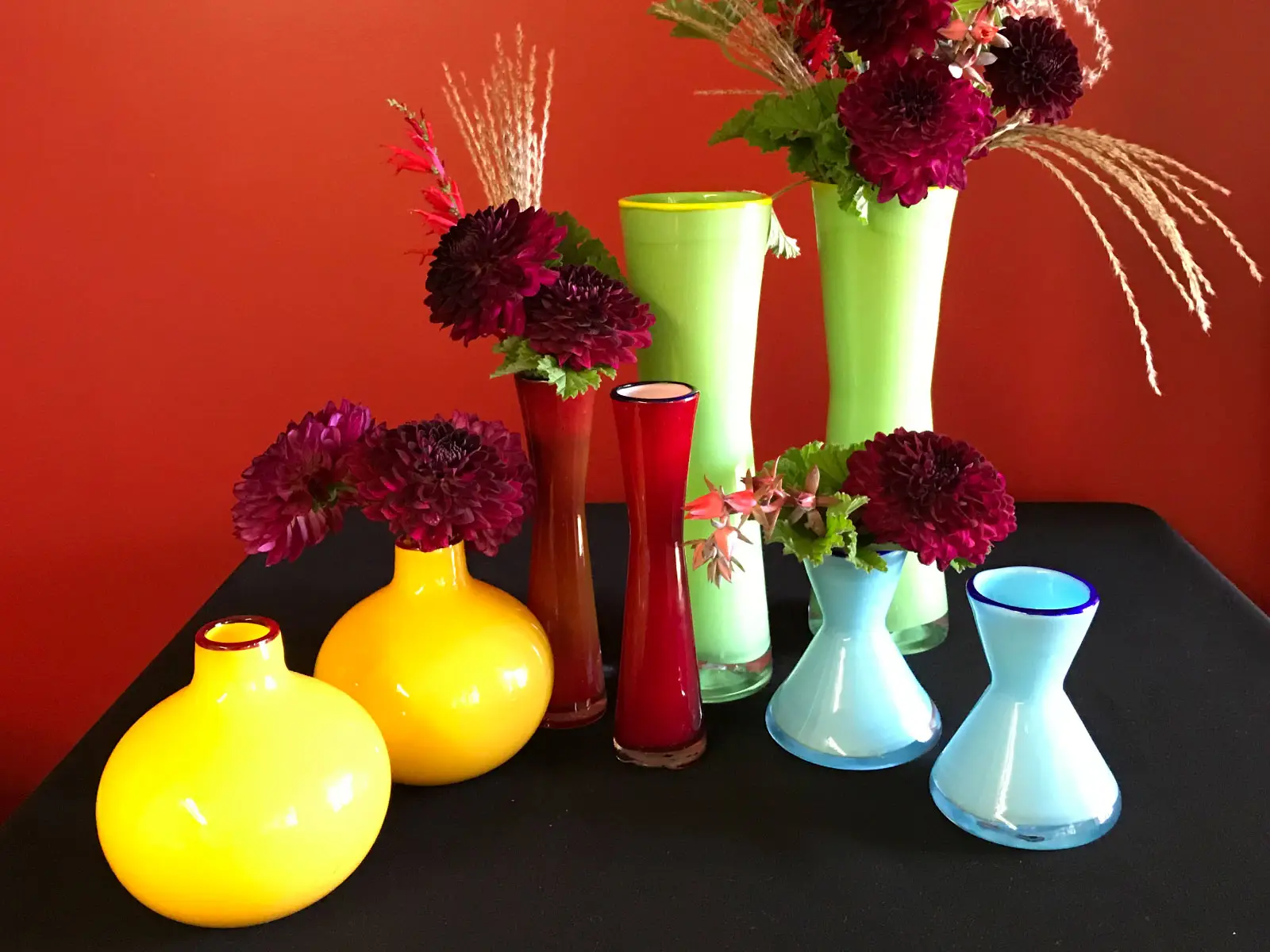 Sets of orange, red, green and blue vases with purple flowers in each one