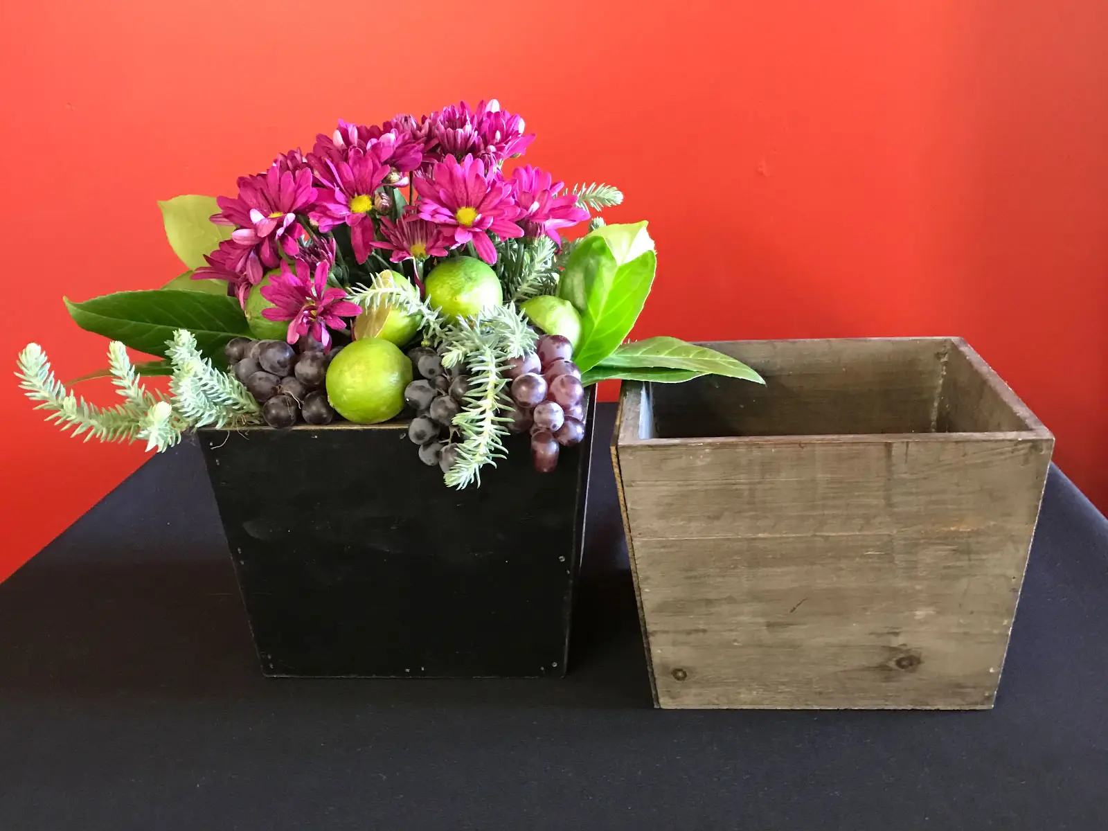 Purple flowers with green leaves, limes and grapes set in a grey box