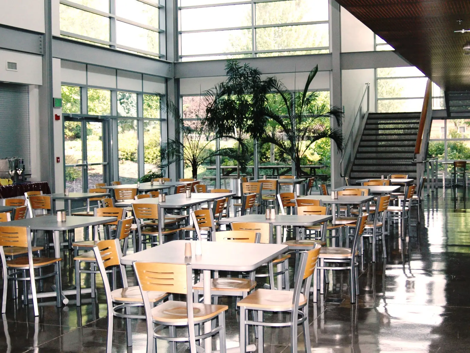 Rows of tables with chairs in the open commons area next to a set of stairs on the Wilsonville campus
