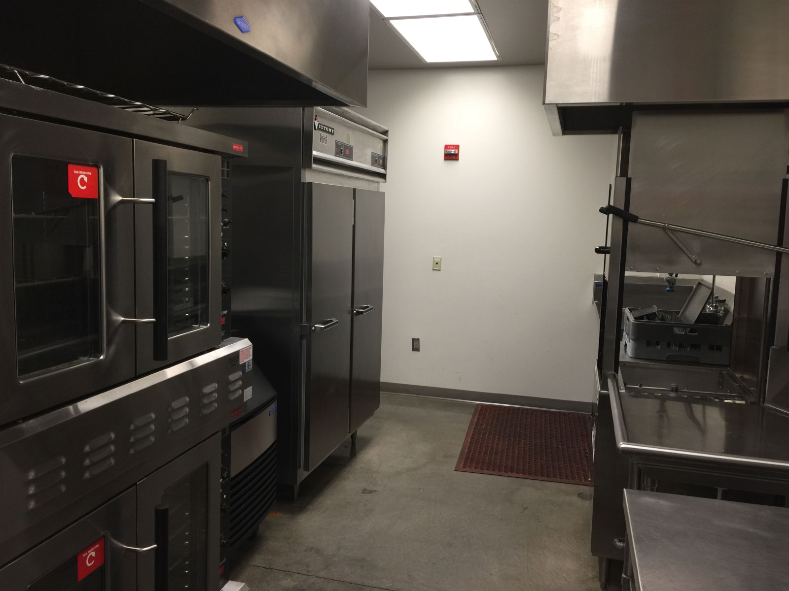 The back area of the Wilsonville campus kitchen area with a refridgerator, dishwasher and heating units