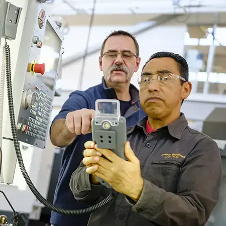 Two people examine manufacuring equipment at CCC's Holden Industrial Technology Center.