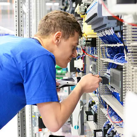 Electronics engineer securing wires to the back of a complex hardware setup.