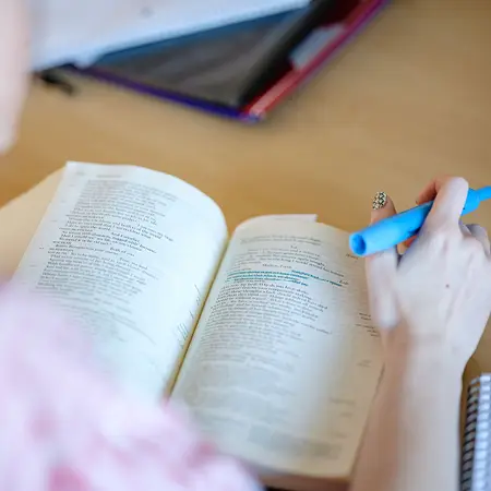 English student reviewing a line they highlighted in blue in their textbook.