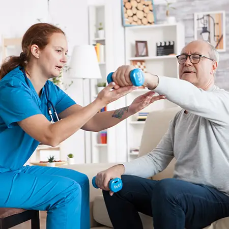 A nurse helps an older patient exercise by showing them how to lift light weights.